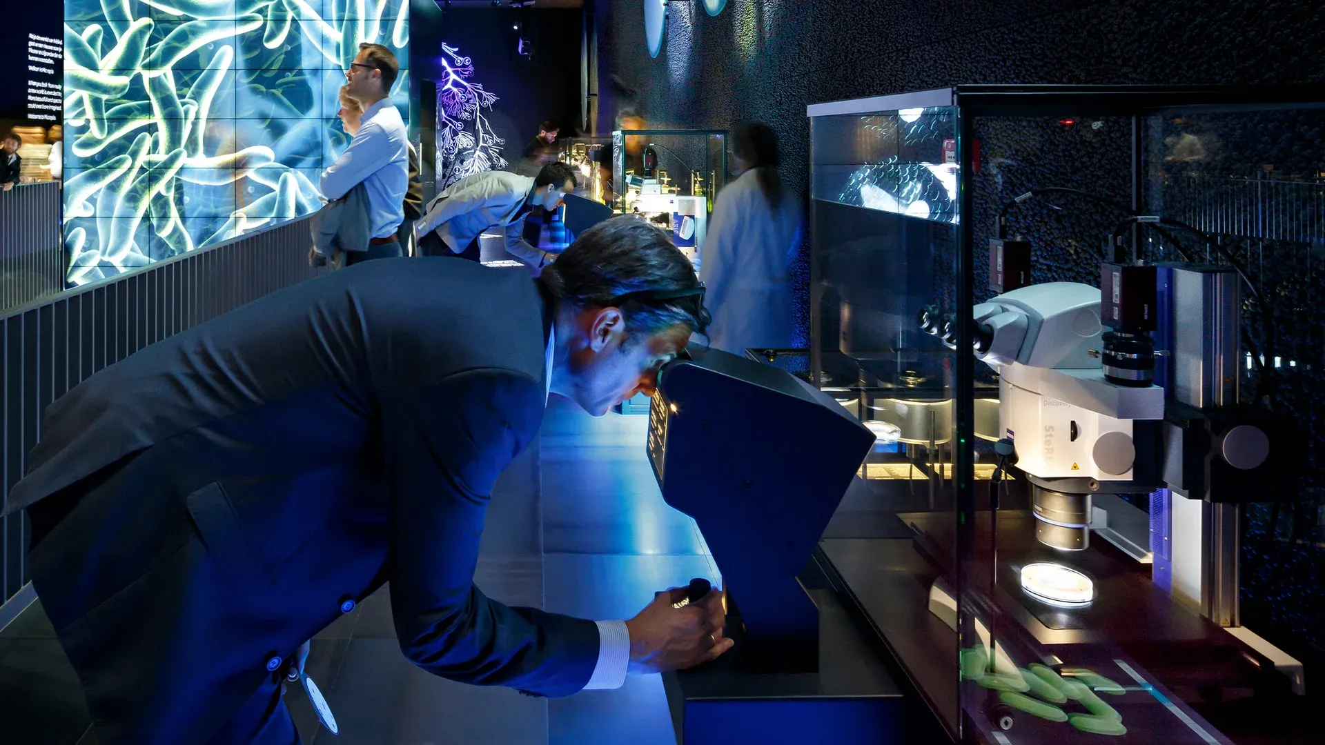 A visitor looking through a microscope at Micropia, surrounded by exhibition displays.